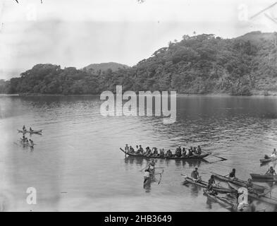 [Canoes, Pango Pango (sic), Samoa], studio Burton Brothers, studio fotografico, 23 luglio 1884, Dunedin, fotografia in bianco e nero, guardando verso il basso su una grande canoa centro a destra, con otto stabilizzatori affollati di fronte ad esso e due più dietro a sinistra. Collina ricoperta di fogliame tropicale che si innalza sullo sfondo da sinistra a destra Foto Stock