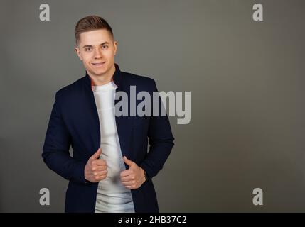 Bel giovane uomo con acconciatura elegante guardando la fotocamera con un sorriso sul viso. Foto di giovane attraente carino moderno freelance Foto Stock