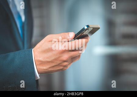 Primo piano della mano di un uomo d'affari con smartphone mobile Foto Stock