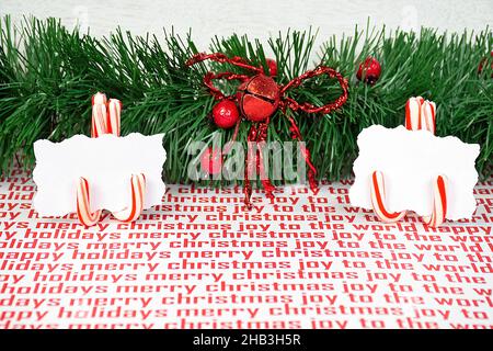 Coppia di porta carte di posto di canna caramella con carte bianche vuote e ghirlande verdi su carta di Natale Foto Stock