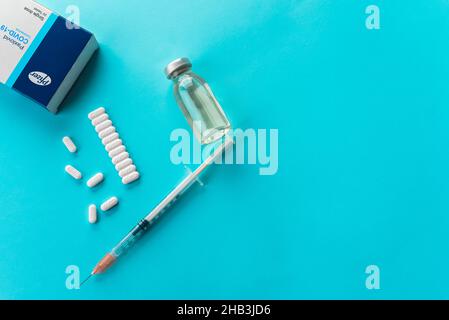 Izmir, Turchia - Novembre 5 2021: Pfizer Covid-19 Paxlovid scatola di trattamento, pillole e vaccino isolato su uno sfondo blu. Foto Stock