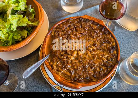 Lo chef Eric Rousselot prepara il famoso Cassoulet Imperial all'Hostellerie Etienne, un'azienda a conduzione familiare dal 1956. Labastide d'Anjou, Francia. La crosta marrone appartiene ad una buona cassoulet. Inoltre, solo una semplice insalata e un bicchiere di vino - c'est tout - c'est bien! Foto Stock