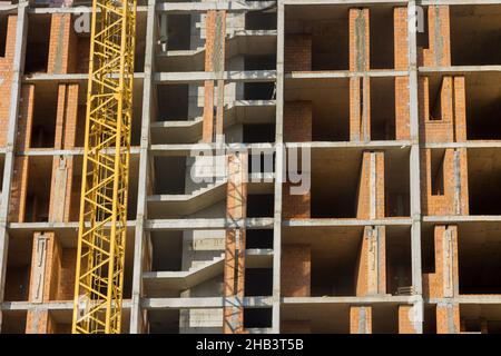 Lungo l'edificio in corso sono in corso lavori di costruzione di un edificio ad appartamenti a più piani Foto Stock