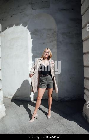 donna bionda in un impermeabile in una passeggiata per la città Foto Stock