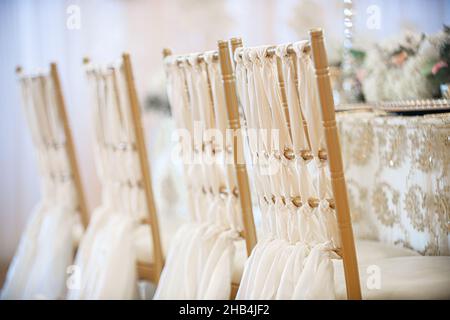 Eleganti sedie chiavari dorate drappeggiato in tela bianca e cena di ricevimento di nozze Foto Stock