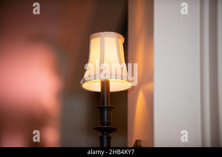 Lampada nera con paralume bianco caldo e luminoso in una stanza accogliente Foto Stock