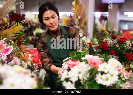 Fiorista femminile asiatico esamina i mazzi in un negozio di fiori Foto Stock