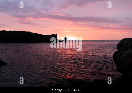 Tramonto sul mare, rocce e sole, silhouette e barca con pescatori. Mare di Azov, Russia. Foto Stock