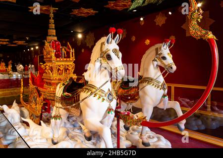 Dubai, Emirati Arabi Uniti, 09.12.2021. Statua di due cavalli bianchi decorati che tirano il carro funerario reale d'oro thailandese (carrozza), esposto all'interno del Padiglione Thailandese Foto Stock