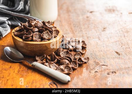Dolci fiocchi di cereali per colazione al cioccolato in ciotola su tavolo di legno. Foto Stock