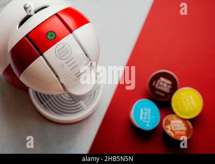 Macchina da caffè Nescafe Dolce gusto con capsule Nescafe Dolce gusto su sfondo rosso e bianco. Messa a fuoco selettiva Foto Stock