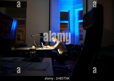 L'uomo workaholic rimane in ufficio straordinario si prepara per la presentazione di affari o il lancio di startup di notte Foto Stock