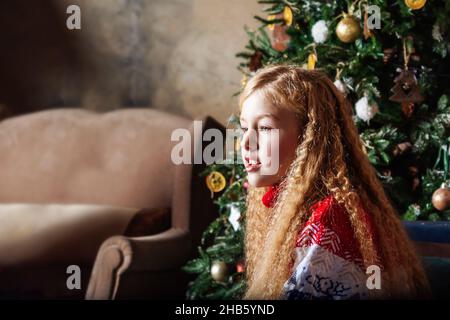 Ragazza adolescente in maglione all'albero di Natale. Foto Stock