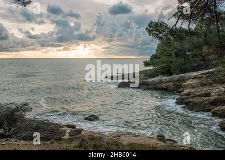 Bellissimo scatto di un mare ondulato sotto un cielo blu nuvoloso durante il tramonto Foto Stock