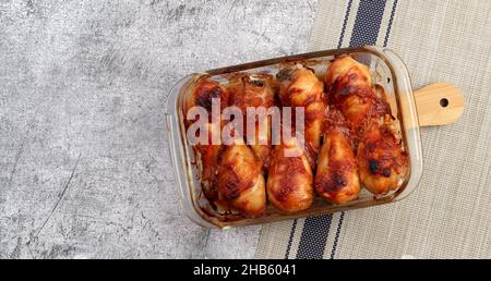 Bastoncini di pollo al forno in una teglia da forno in vetro su sfondo grigio scuro. Vista dall'alto, piatto Foto Stock