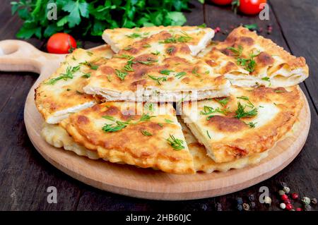 Khachapuri con formaggio caserma e verdure a bordo. Piatto nazionale georgiano. Foto Stock