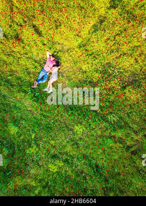 Vista dall'alto della coppia felice che giace sull'erba in estate Park.Couple in amore trascorrere il tempo insieme all'aperto. Rapporti antenna verticale shot Foto Stock