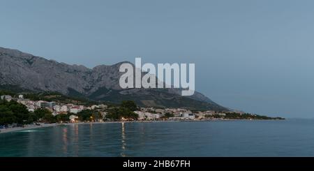 Località turistica Baska Voda sulla costa adriatica sotto il monte Biokovo in Croazia, al crepuscolo in estate Foto Stock