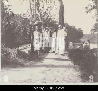 Percorso lungo l'acqua, alcuni olandesi, tra cui Maria Gonggrijp, su un sentiero lungo un fiume. Sul sentiero, una donna surinamese con un cesto sulla testa si trova accanto ad una canoa, 1911. Parte dell'album fotografico della famiglia Boom-Gongrijp a Suriname e Curao., Andries Augustus Boom, anonimo, Suriname, 1911, supporto fotografico, altezza 87 mm x larghezza 103 mm Foto Stock