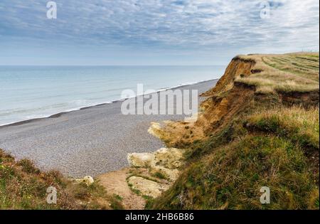 Erodendo, scogliere sgretolanti e la spiaggia di pietra e la costa sul sentiero della costa Norfolk a Weybourne, costa nord di Norfolk, East Anglia, Inghilterra Foto Stock