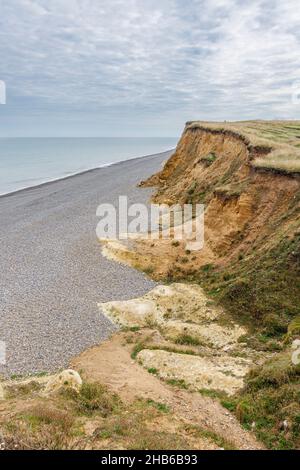 Erodendo, scogliere sgretolanti e la spiaggia di pietra e la costa sul sentiero della costa Norfolk a Weybourne, costa nord di Norfolk, East Anglia, Inghilterra Foto Stock