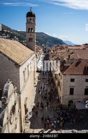 Vista verso la strada di Stradun a Dubrovnik, Croazia che mostra la chiesa campanile, turisti e vacanzieri Foto Stock