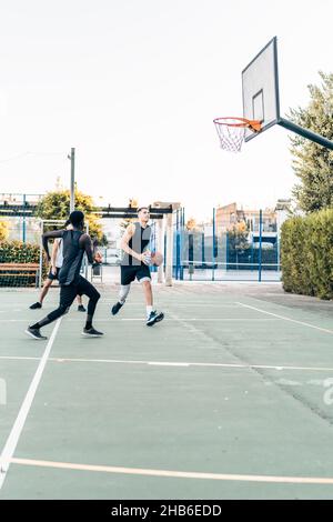 Foto verticale di un gruppo di amici che giocano a basket in uno spazio all'aperto Foto Stock