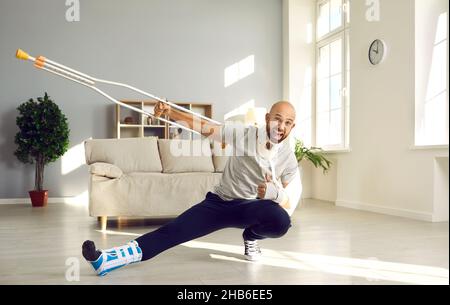 L'uomo felice che è sul congedo ammalato dovuto le sue lesioni sta tenendo la stampella e mostrando i pollici-in su Foto Stock