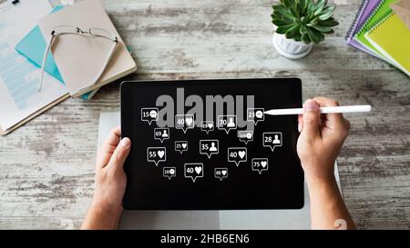 SMM, concetto di social media marketing. Mi piace, commenti e nuove icone di follower sullo schermo del dispositivo. Foto Stock