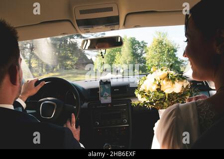 Primo piano vista sposa e sposo in auto guidare al matrimonio festa per incontrare amici all'aperto . La coppia di nozze celebra il matrimonio in Lituania Foto Stock