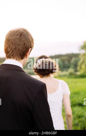 ritratto all'aperto di giovani sposi che camminano sul prato verde Foto Stock