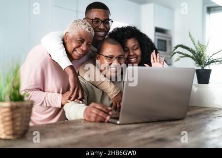 Felice famiglia ispanica divertirsi a videochiamare con i genitori utilizzando il laptop a casa - tecnologia e comunicazione concetto Foto Stock