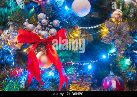 Albero di Natale decorato con coloratissime ghirlande luminose, giocattoli e palloncini da vicino. Sfondo di Natale. Messa a fuoco selettiva. Foto Stock