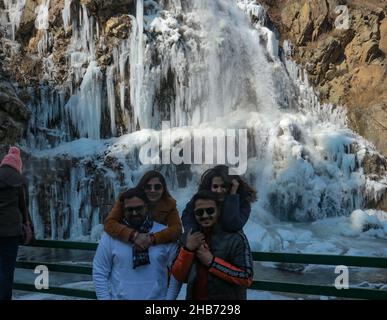 Srinagar, India. 17th Dic 2021. I visitatori si posano di fronte a una cascata ghiacciata il 17 dicembre 2021 a Drung, ad ovest di Srinagar, la capitale estiva del Kashmir indiano. Il mercurio nel Kashmir è crolmeted a meno 12,3 °C, rendendolo il primo-più basso notte di dicembre.l'uomo del tempo ha previsto principalmente il tempo asciutto sopra Jammu e Kashmir e Ladakh per i prossimi giorni, post 'Chillai-Kalan', il periodo di 40 giorni dell'inverno più arshest in Kashmir, che inizia il 21 dicembre. (Foto di Sajad Hameed/Pacific Press) Credit: Pacific Press Media Production Corp./Alamy Live News Foto Stock