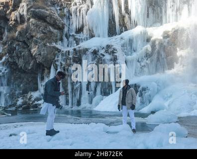 Srinagar, India. 17th Dic 2021. I visitatori si posano di fronte a una cascata ghiacciata il 17 dicembre 2021 a Drung, ad ovest di Srinagar, la capitale estiva del Kashmir indiano. Il mercurio nel Kashmir è crolmeted a meno 12,3 °C, rendendolo il primo-più basso notte di dicembre.l'uomo del tempo ha previsto principalmente il tempo asciutto sopra Jammu e Kashmir e Ladakh per i prossimi giorni, post 'Chillai-Kalan', il periodo di 40 giorni dell'inverno più arshest in Kashmir, che inizia il 21 dicembre. (Foto di Sajad Hameed/Pacific Press) Credit: Pacific Press Media Production Corp./Alamy Live News Foto Stock