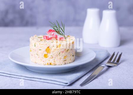 Insalata di granchio con mais e uova su un piatto bianco. Servire a porzioni. Insalata russa tradizionale. Primo piano. Foto Stock