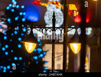 Due luci per lo shopping vintage in stile retrò. Lampade con decorazioni natalizie illuminate e pupazzo di neve illuminato dietro la messa a fuoco. Foto Stock
