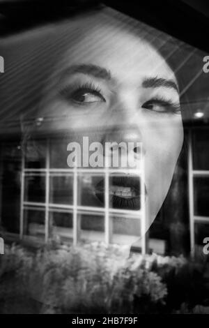 Immagine in scala di grigi del riflesso specchio di una bella donna dell'Asia orientale Foto Stock