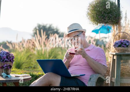 Happiness Man sorpresa matrimonio proposta online per ragazza online attraverso il computer portatile. Pensione barba grigia matura o uomo anziano in rosa e cappello Foto Stock