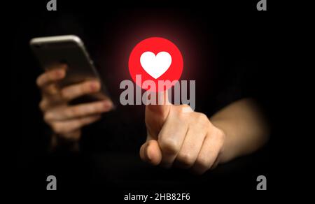 Concetto di social media. Premere a mano pulsante simile, icona di notifica. Social networking, sfondo nero Foto Stock