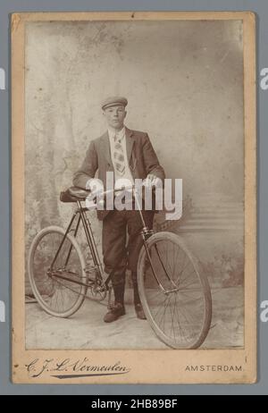 Studio ritratto di un uomo sconosciuto con una bicicletta, Cornelis Johannes Lodewicus Vermeulen (menzionato sull'oggetto), Amsterdam, c.. 1895 - c. 1910, supporto fotografico, cartone, altezza 145 mm x larghezza 97 mm Foto Stock