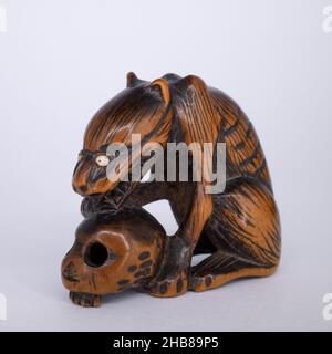 Antico Netsuke di legno giapponese di un lupo con un cranio umano. Periodo Edo, 19th secolo Foto Stock