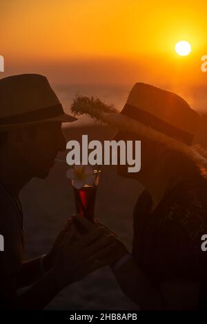 Un uomo e una donna bevono un cocktail al tramonto sul mare. Messa a fuoco selettiva. Foto Stock