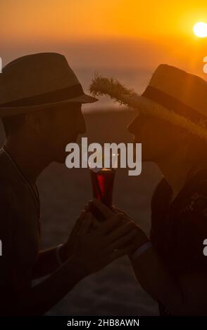 Un uomo e una donna bevono un cocktail al tramonto sul mare. Messa a fuoco selettiva. Foto Stock