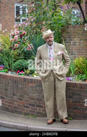 Un uomo in estate vestito e cappello in piedi di fronte ai fiori Foto Stock