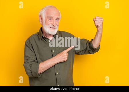 Foto di persona bella positiva indica dito braccio flettente bicipiti isolato su sfondo giallo Foto Stock