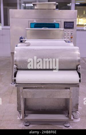 Panettiere per la preparazione di pasta su pasta sfoglia. Rotolatrice per pasta per la produzione di pasticceria, pane e baklava. Foto Stock