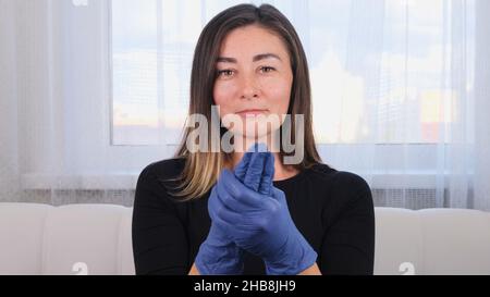 Donna in guanti di protezione blu con disinfettante per gel lavavetri per prevenire epidemie di virus o agenti antibatterici. Foto Stock