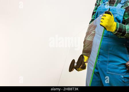 Glazier che tiene nelle mani un pezzo di vetro spesso con l'aiuto di una speciale ventosa, sfondo luminoso, molto spazio per l'iscrizione Foto Stock