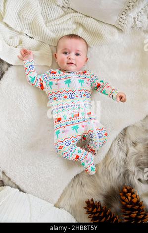 Bambina (0-1 mesi) in pigiami sdraiati a letto Foto Stock